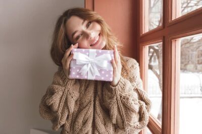 A sorority girl holding a gift by a window.